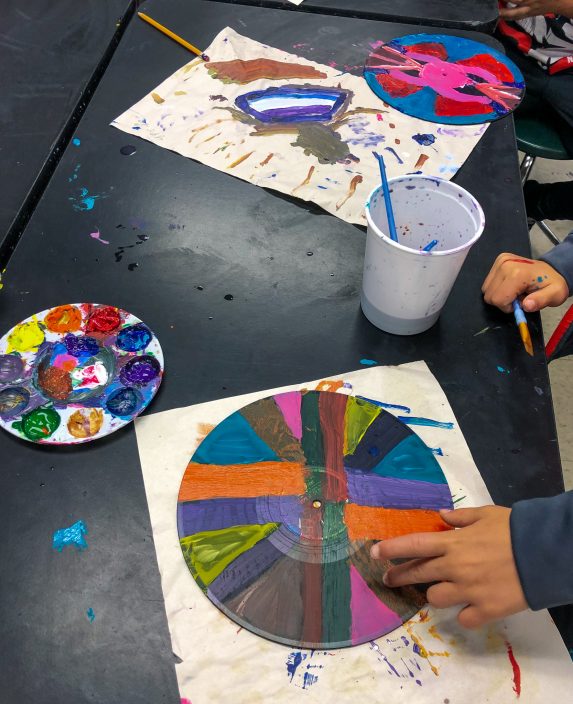 students painting round discs