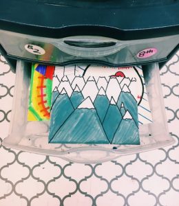drawer with colorful drawings inside, mountain drawing on top