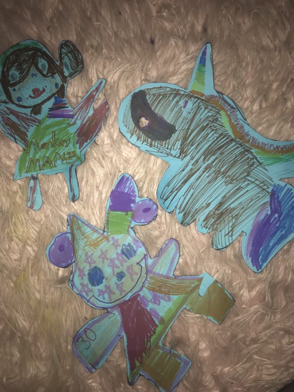 3 cut out drawings of a shark, doll, and clown