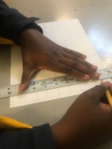 student hands drawing grid on paper
