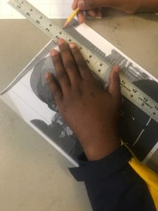 student hands drawing grid over image