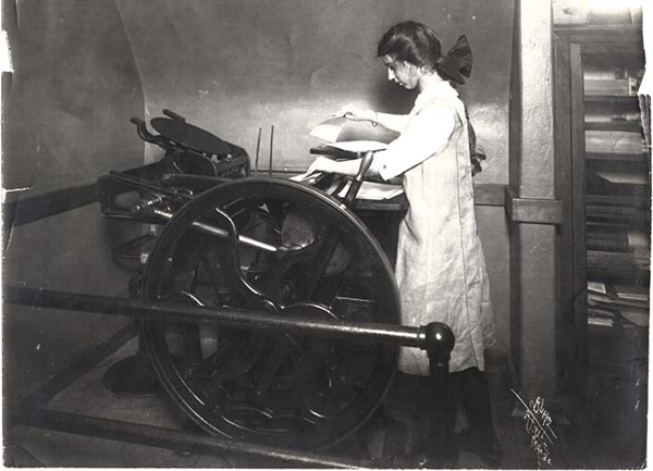 An eighth grade girl uses a printing press in 1910.