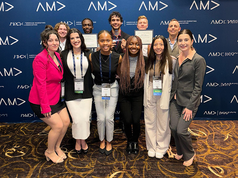 Group of students posing in front of blue AMA backdrop