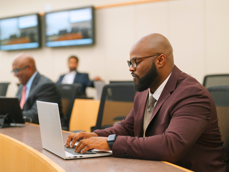 a Master of Decision Analytics student working on a laptop in a classroom in Snead Hall