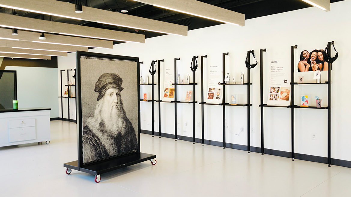 An image from inside the Shift Retail Lab. Theres a large portrait of Leonardo da Vinci to the left and a wall full of black shelves with students projects on them to the right.