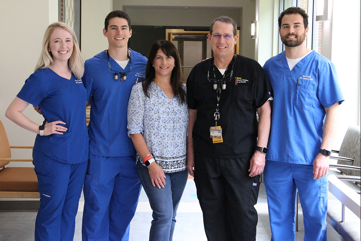 Katie Veltman stands with Joey, Cris, Al and David Russell in a hallway in the dental school. 