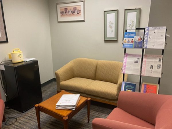 A room with seating, a coffee table, mini fridge and decorations on the walls.