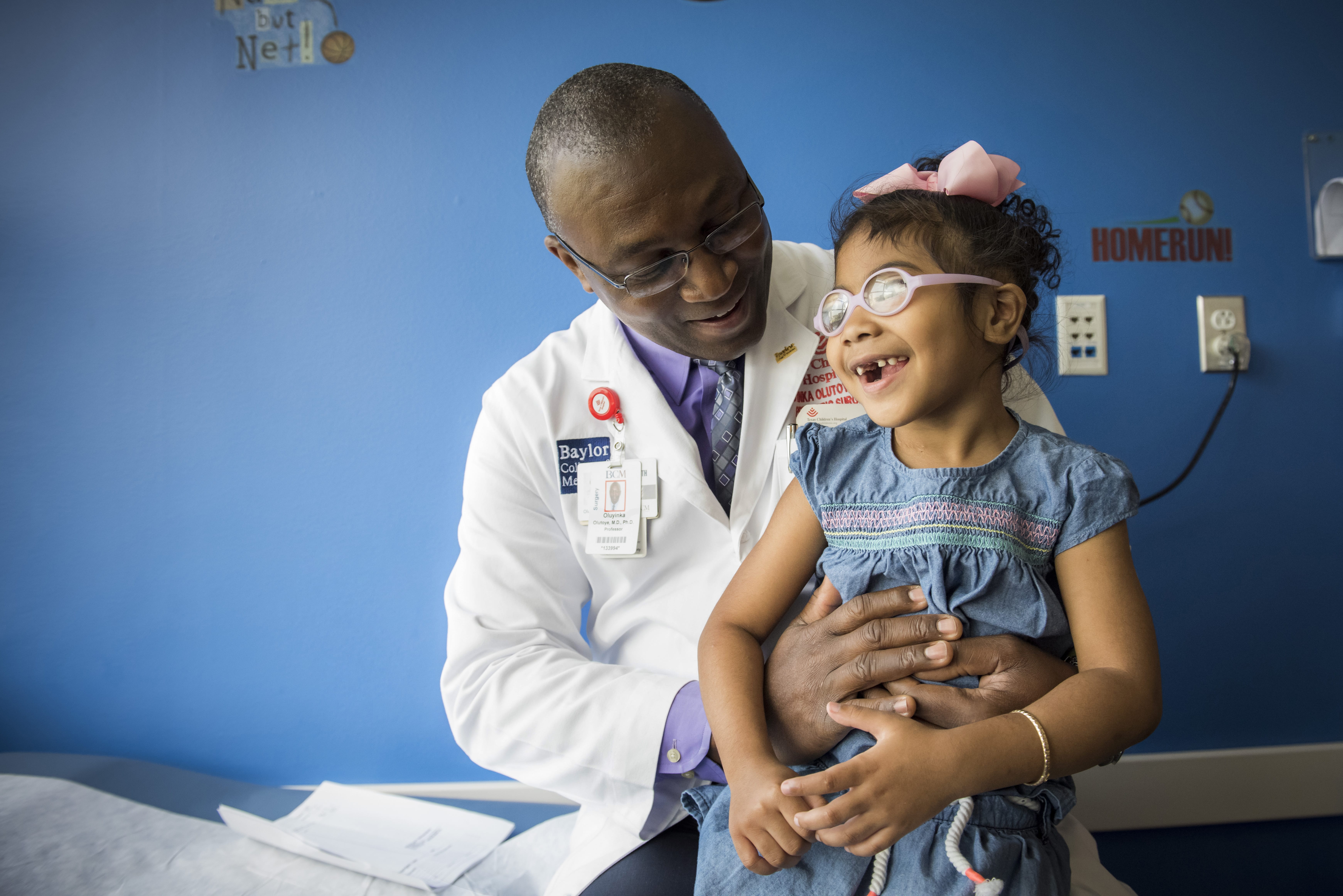 A doctor holds a smiling child.