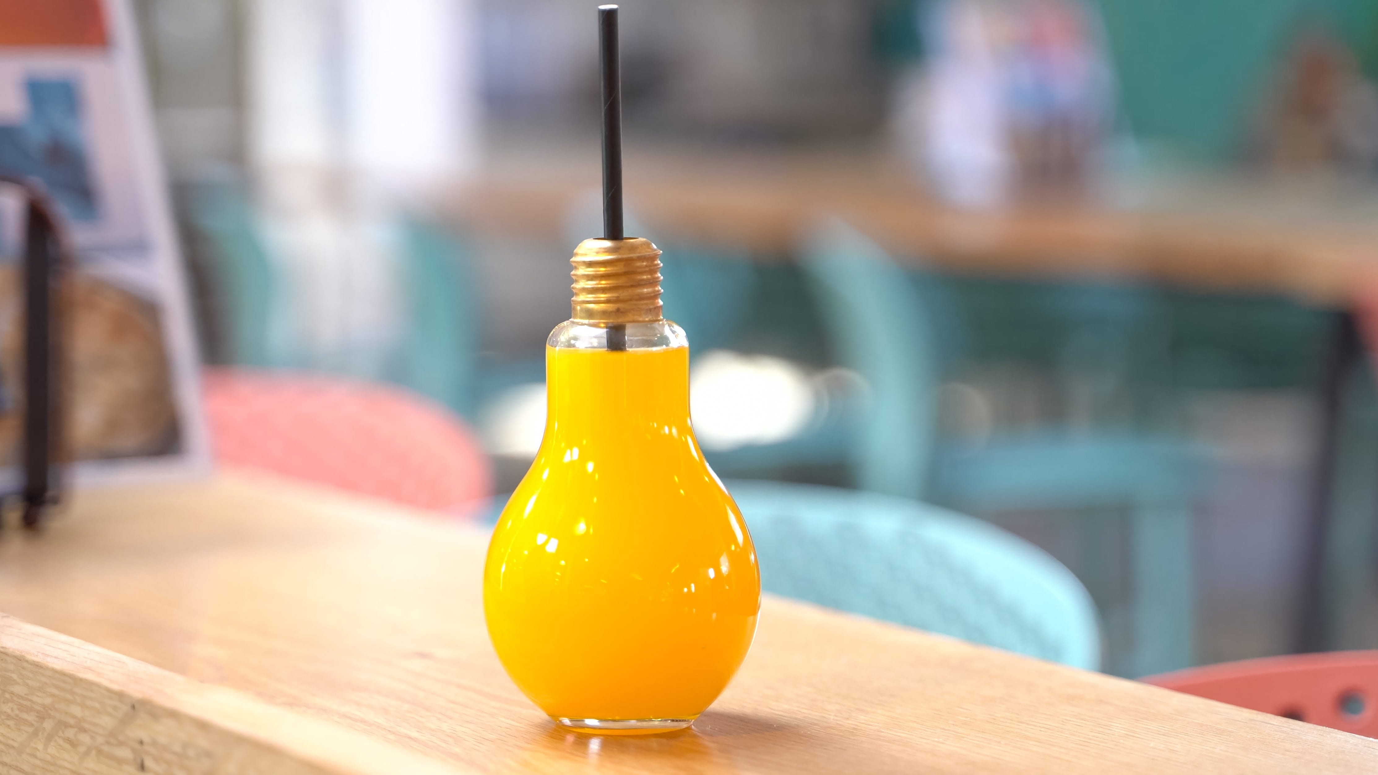 An orange drink made in a lightbulb shaped glass.