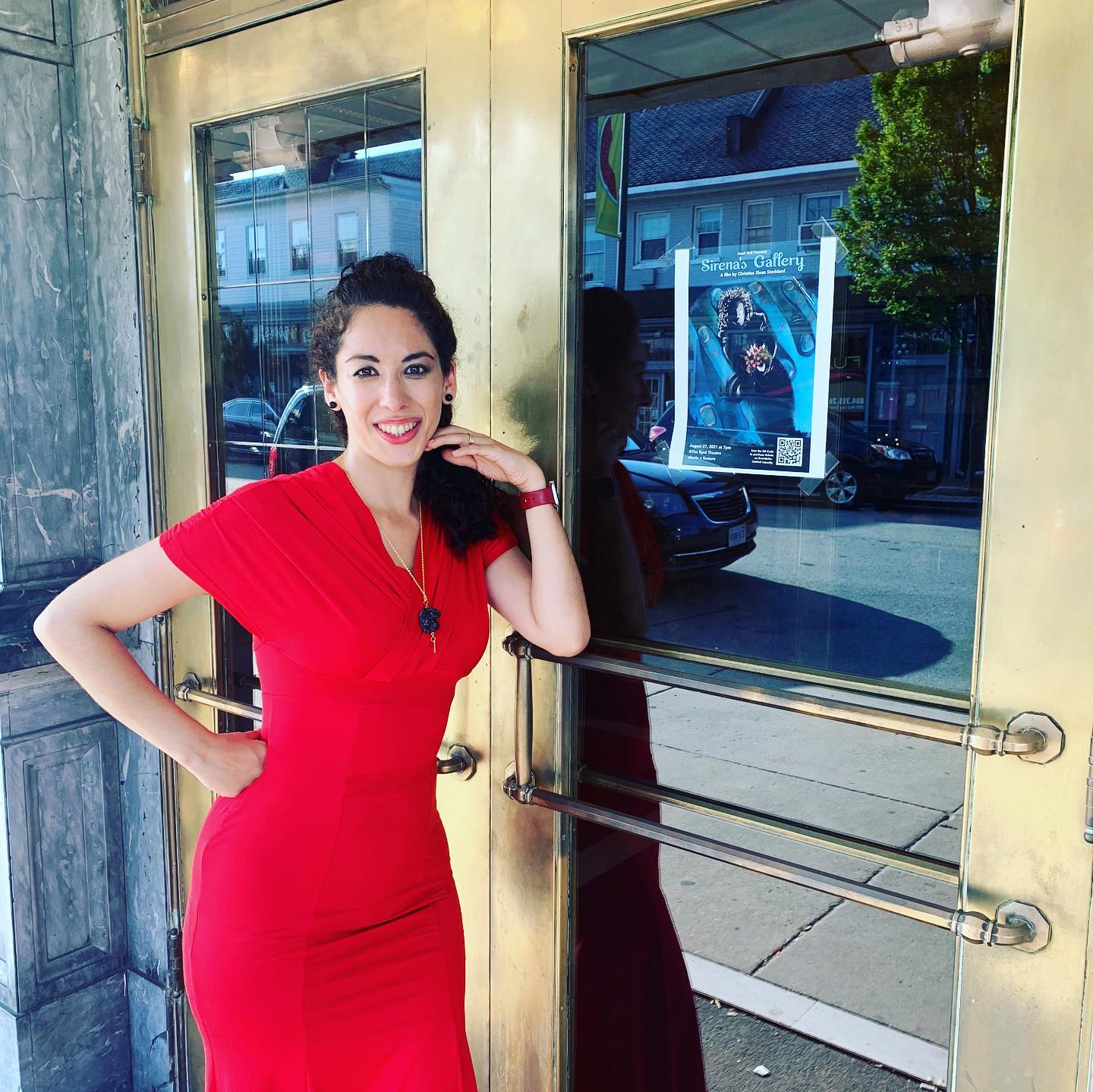 Christine Stoddard, wearing a red dress, standing outside of Richmond's Byrd Theater.