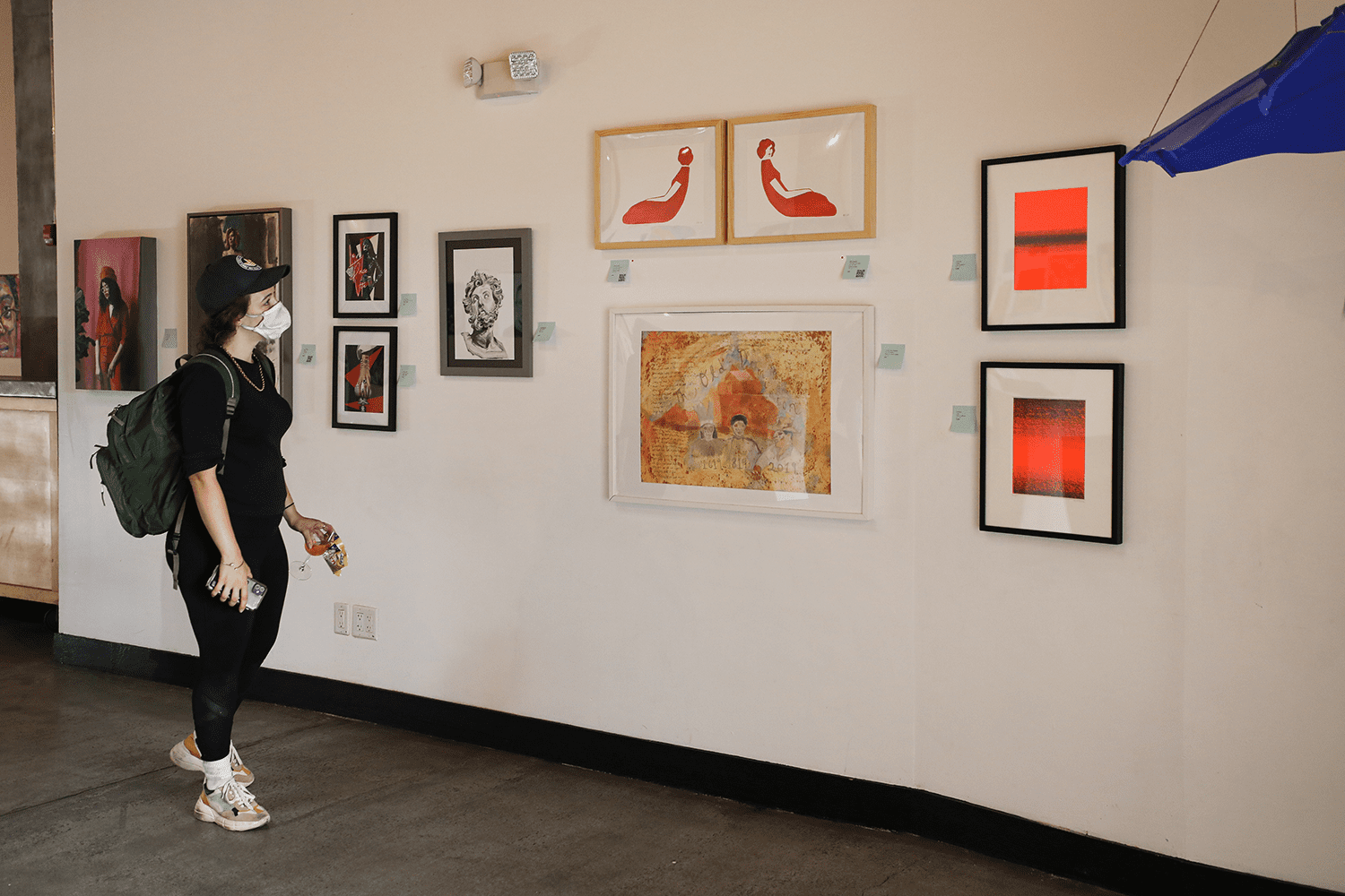 A person looks at an art gallery wall covered in various paintings and pieces.