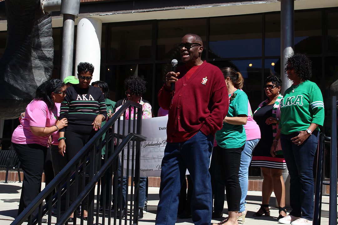 Rodney Harry holding a microphone while speaking at the African American Alumni Council Reunion