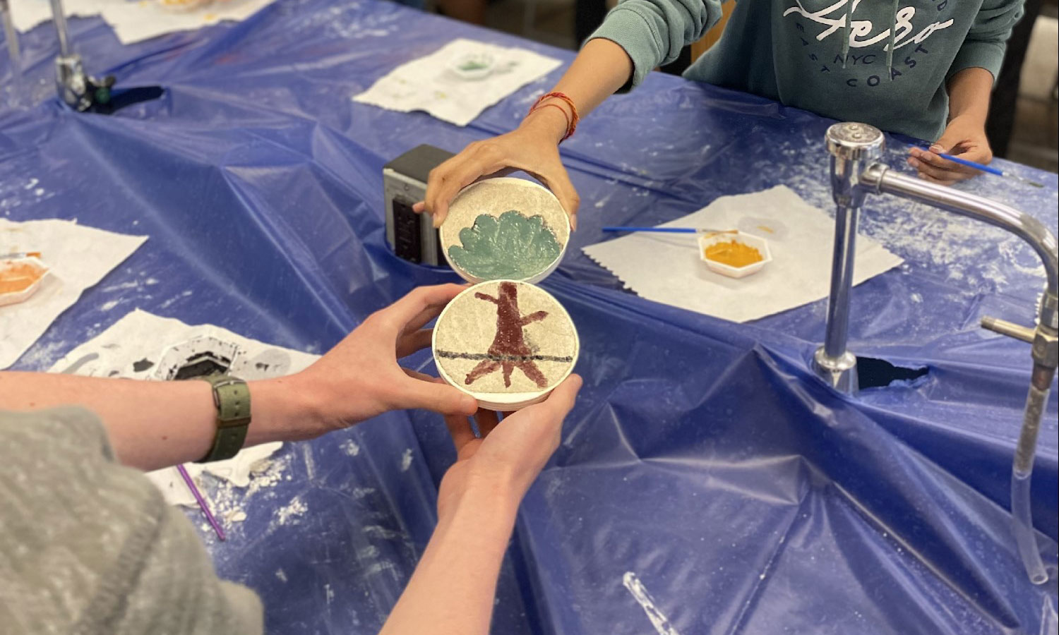 Students holding up their freshly painted frescos.