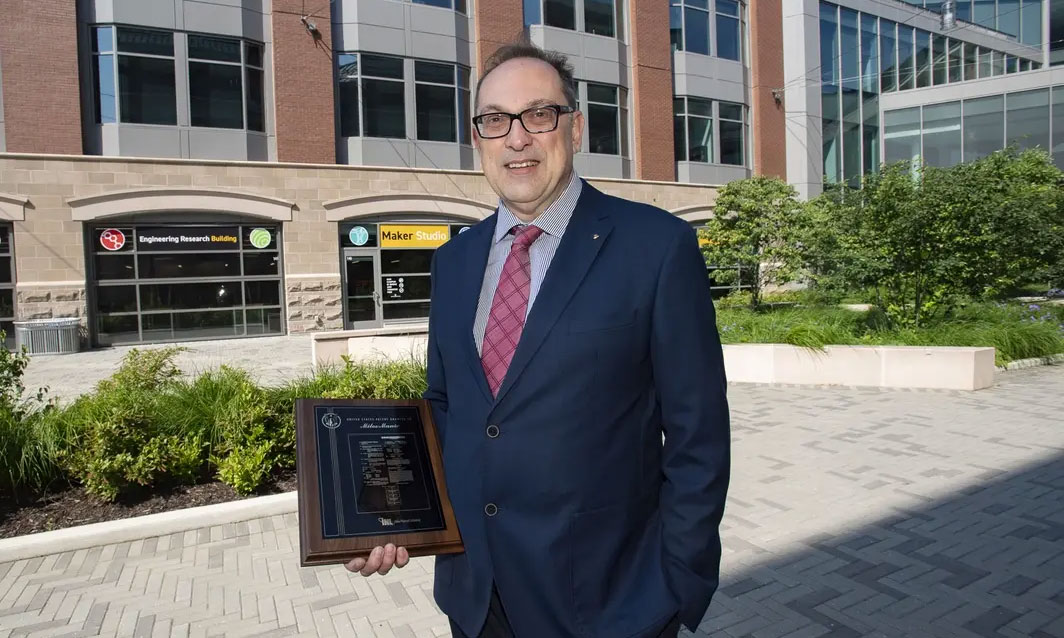 Manic holding a plaque from one of his patents. (Photo by Tom Kojcsich, Enterprise Marketing and Communications)