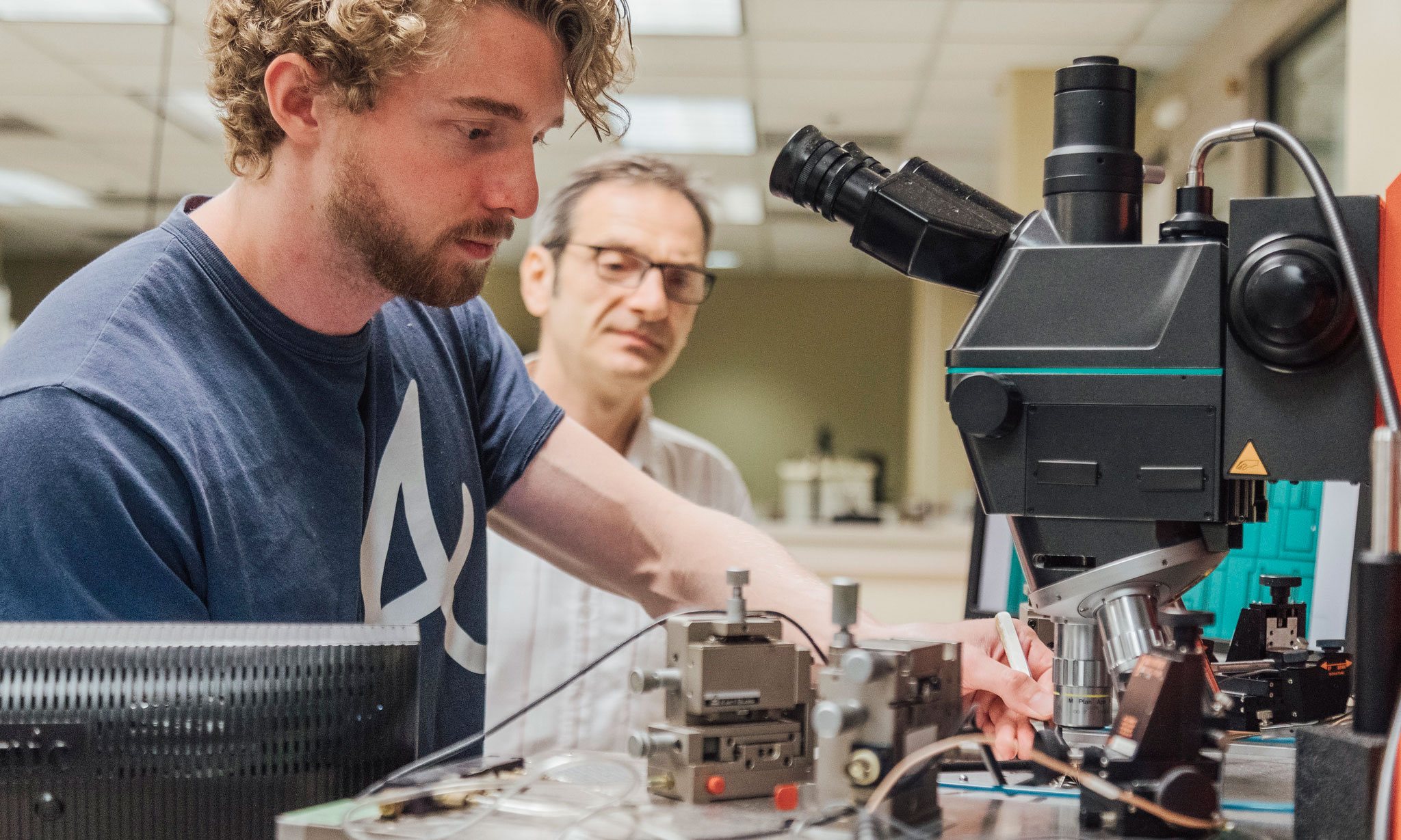 Student working with a microscope with the assistance of Umit Ozgur