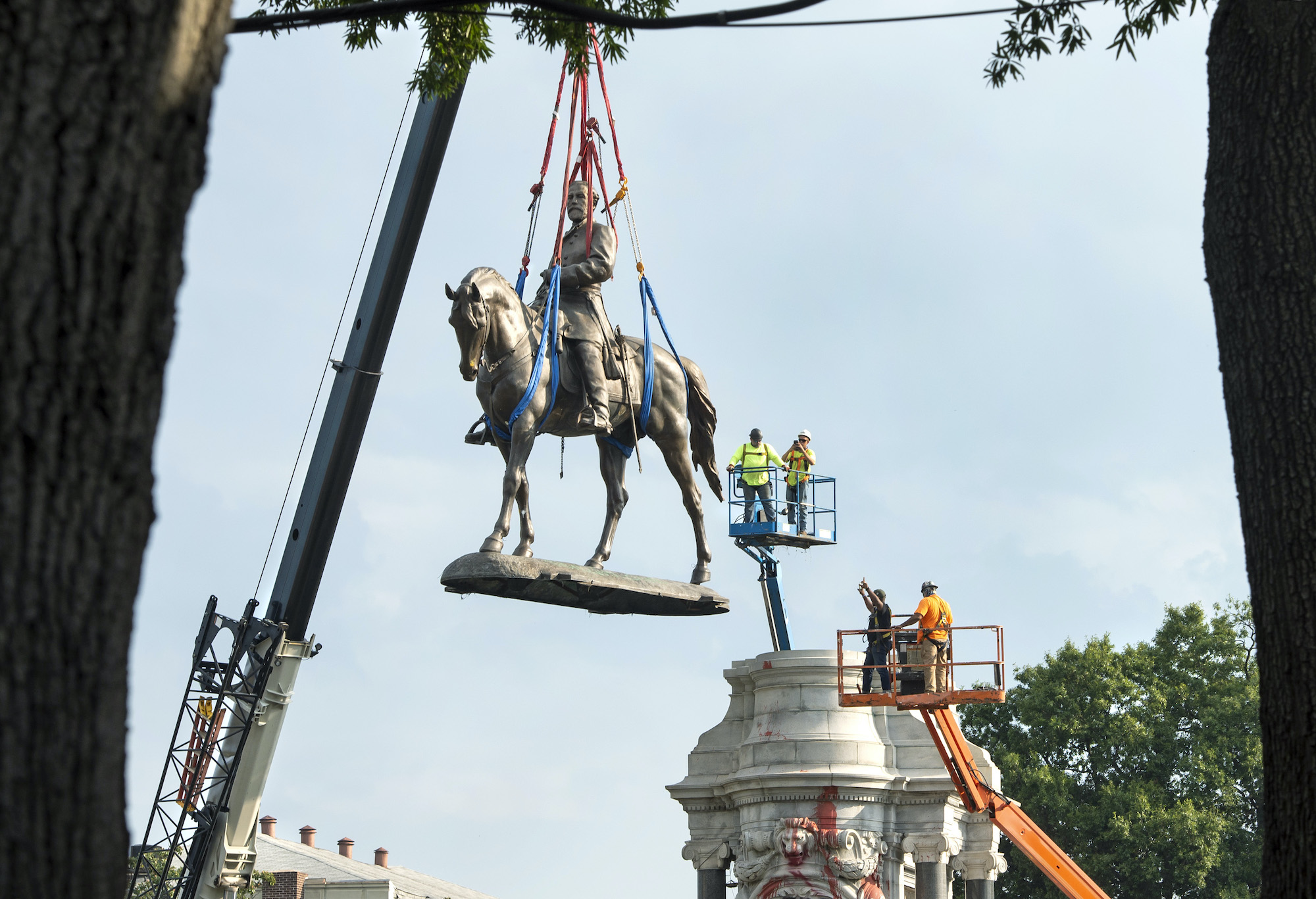 The Robert E. Lee monument hanging in the air as it is removed from the statue's base.