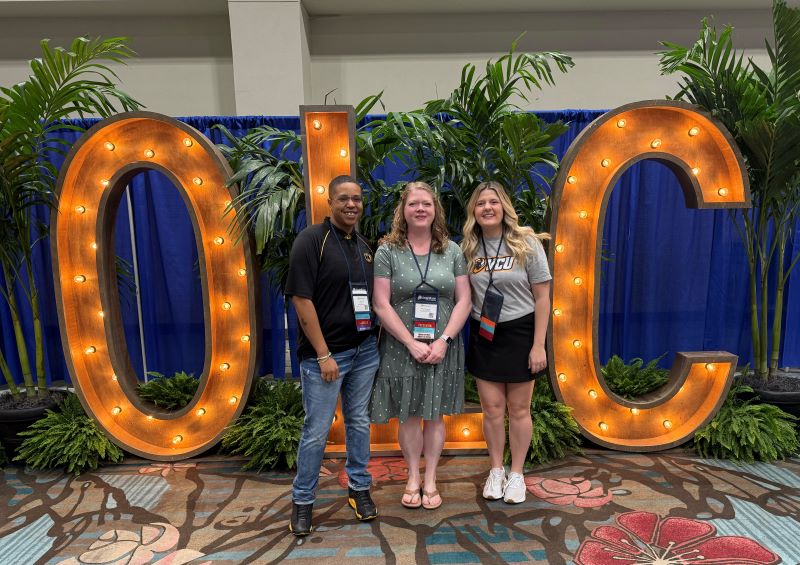 Picture of three people in front of OLC sign