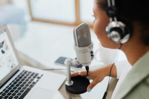 Person speaking into professional microphone looking at laptop
