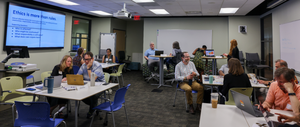 Photograph cropped wide shot of a modern classroom with instructional designers working with faculty at multiple tables.
