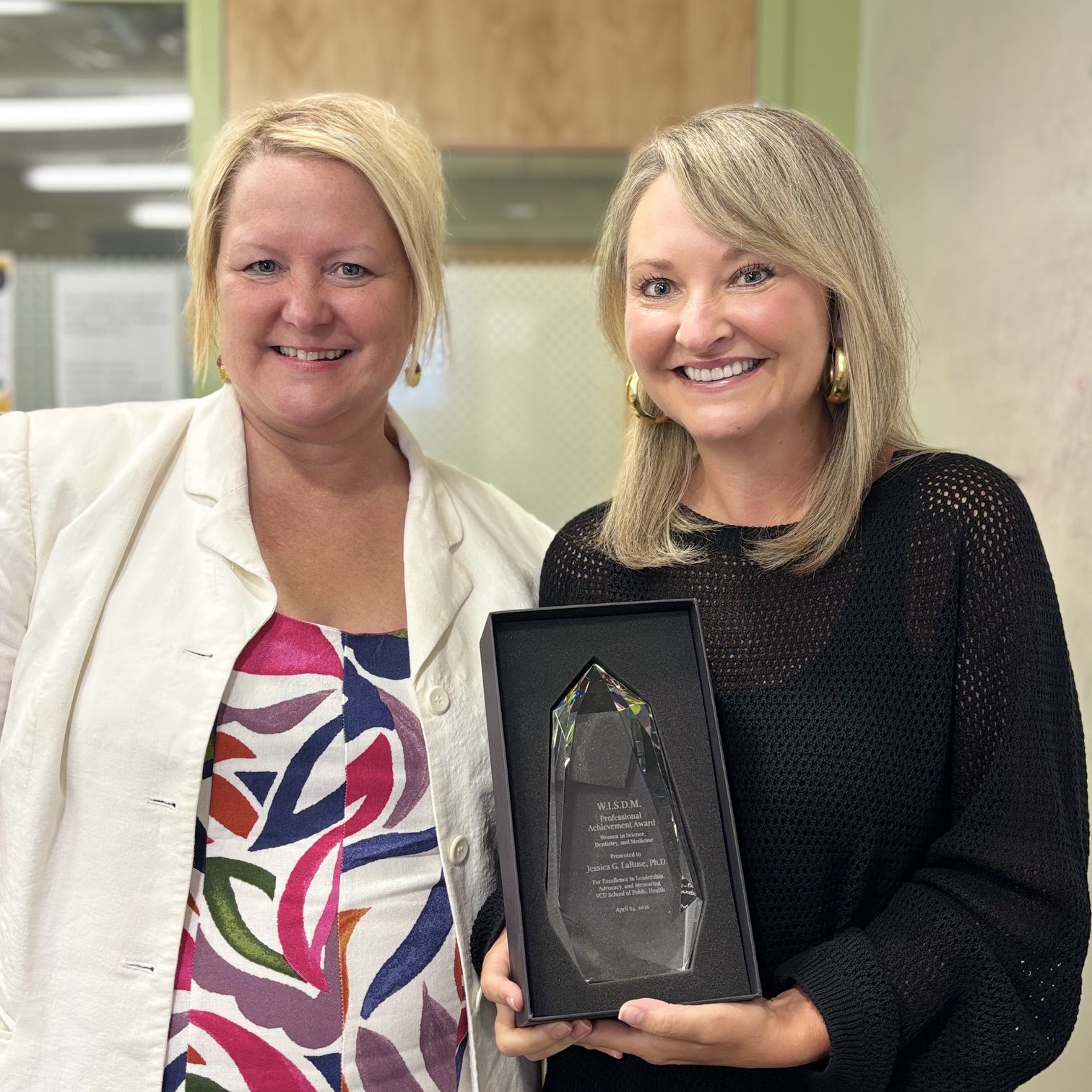 Image of two people, one holds an award trophy