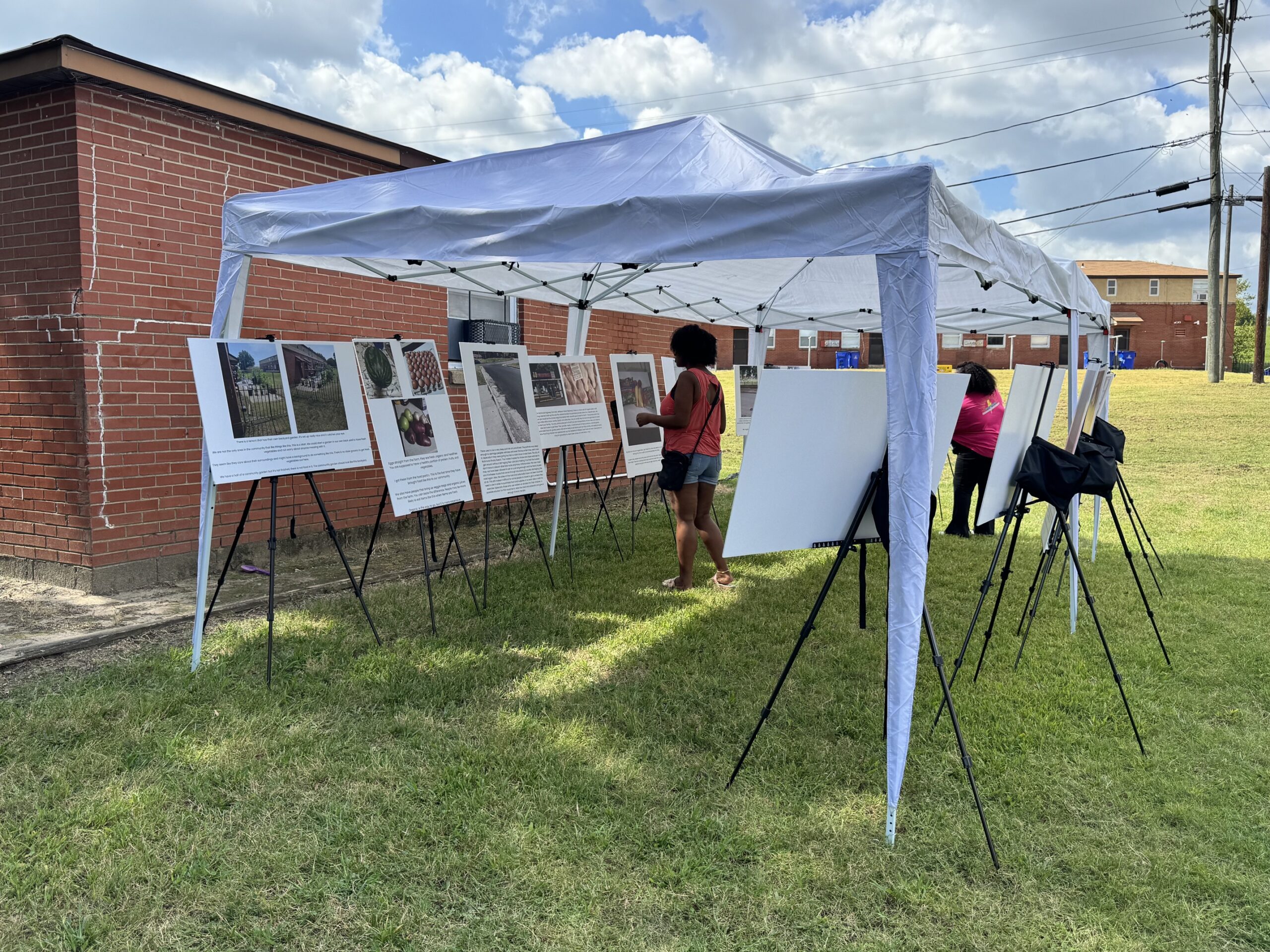Image of a person standing under a tent looking at large posterboards on easels