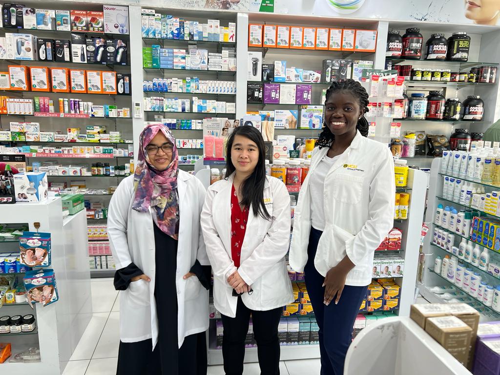 A pharmacist and two pharmacy students on an international rotation pose for a photo in a United Arab Emirates pharmacy.