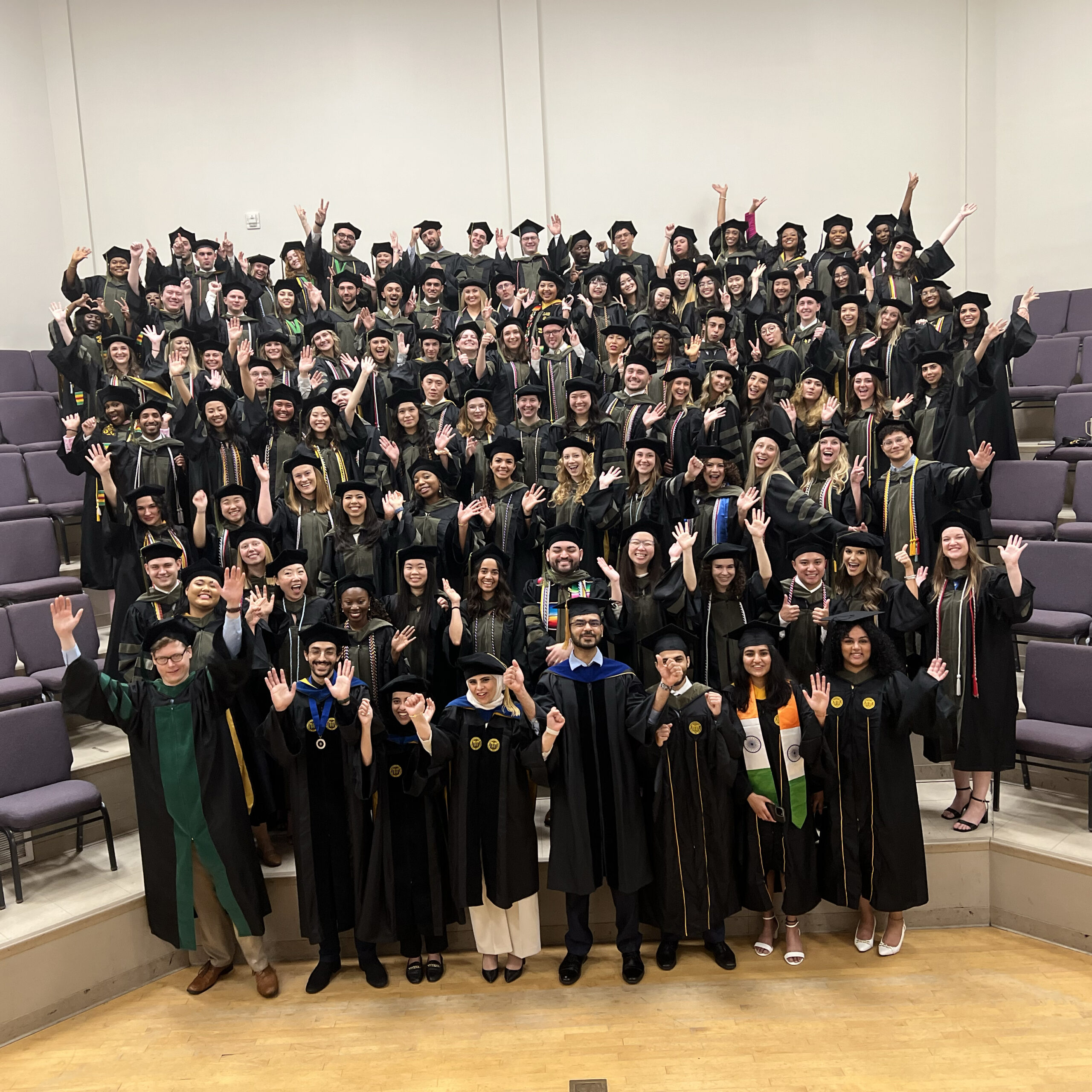 The Class of 2024, standing on risers, pose for a celebratory photo before the VCU School of Pharmacy Hooding and Diploma Ceremony.
