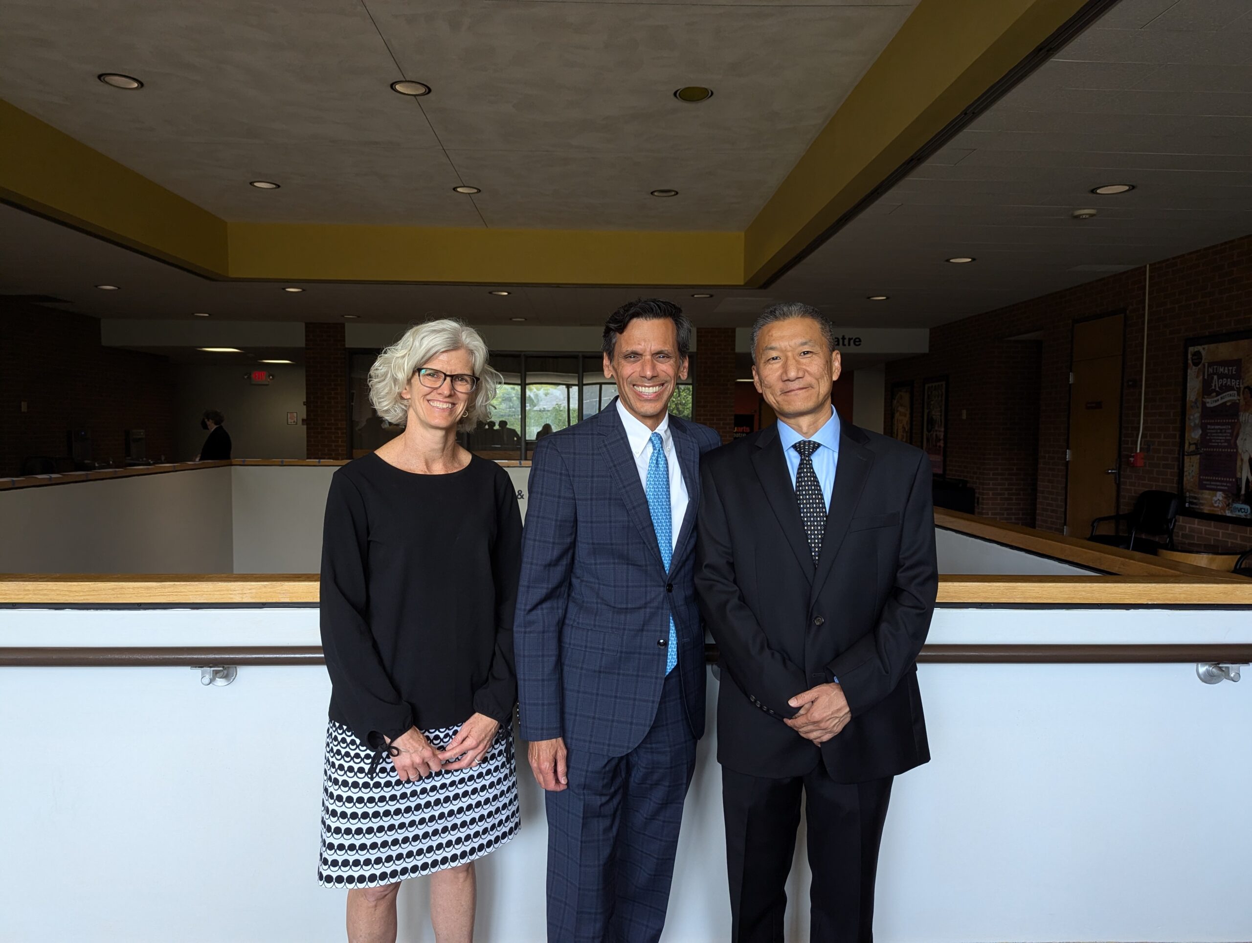 Three people in business attire pose for a photo, including awardee Yan Zhang.