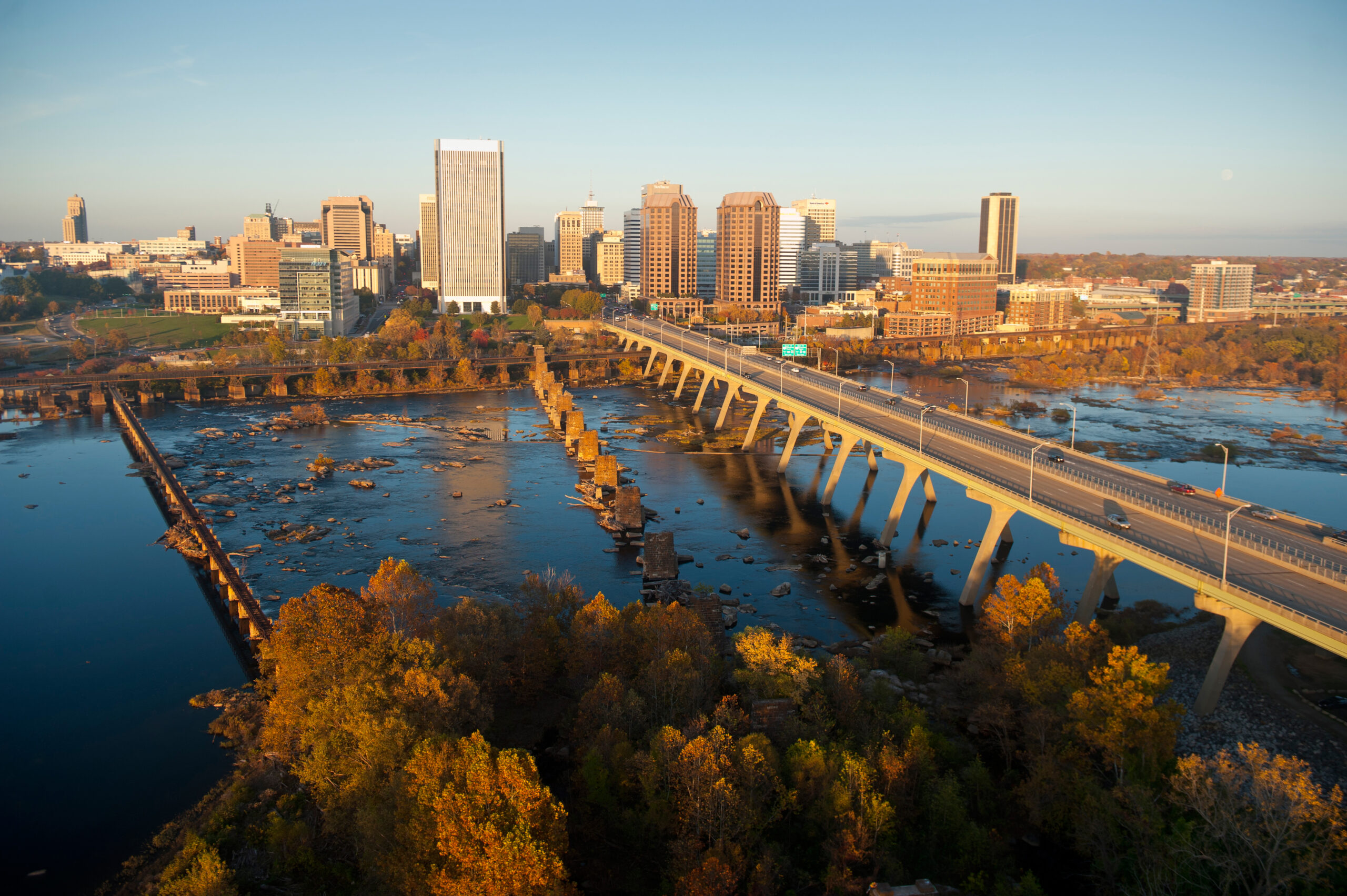 Image of a bridge crossing a river with a city skyline in the background.