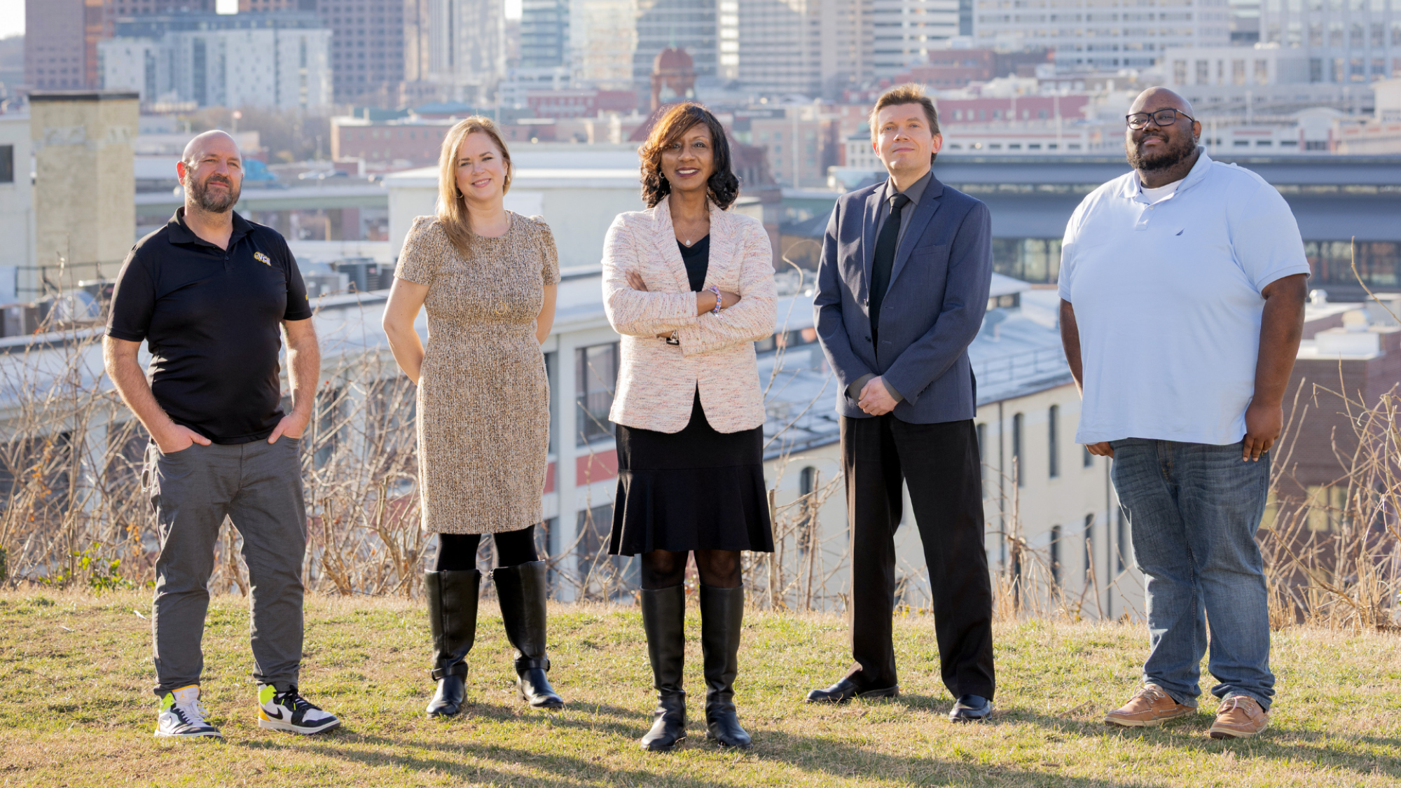 Photograph of 5 people standing in front of a city skyline