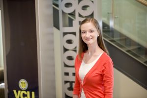Mackenzie Waters stands in front of VCU Social Work sign in the Academic Learning Commons
