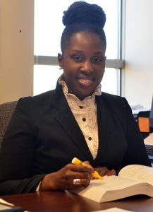Dr. Goings sitting at a table with a book and highlighter, wearing a dark jacket and white blouse.