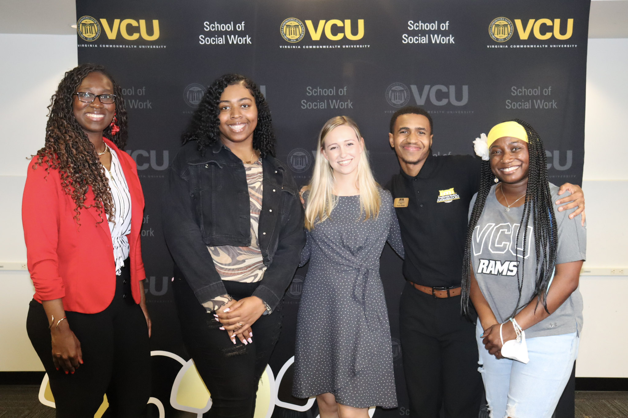 Five social work students pose in front of a VCU School of Social Work backdrop