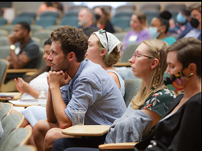 A social work student rests his chin in his hand as he listens to a speaker