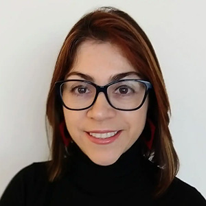 Headshot of Paola Roldan, wearing glasses and black turtle neck. 
