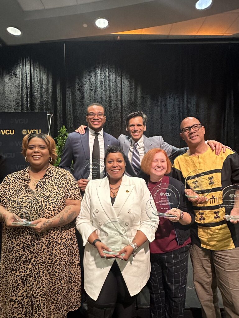 Five award recipients, holding their awards, stand with VCU President Michael Rao