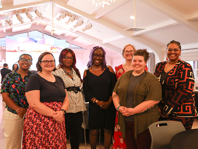 A group of seven people pose standing together. 