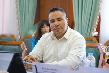 Dr Jose Trevino sits with his hands folded in front of him at a table, wearing a white button-down shirt.