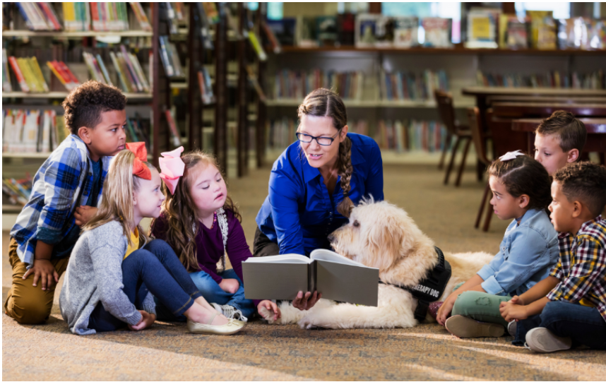 Image of children and teacher reading with a service dog