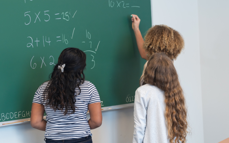 Students writing math equations on a chalkboard