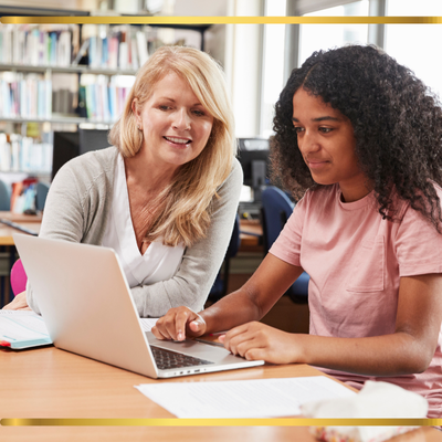 Teacher working with a student looking at a laptop