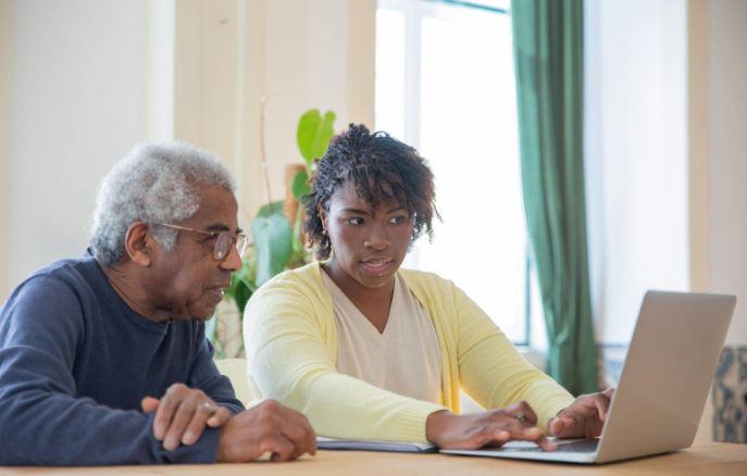 Image of two people looking at a laptop screen