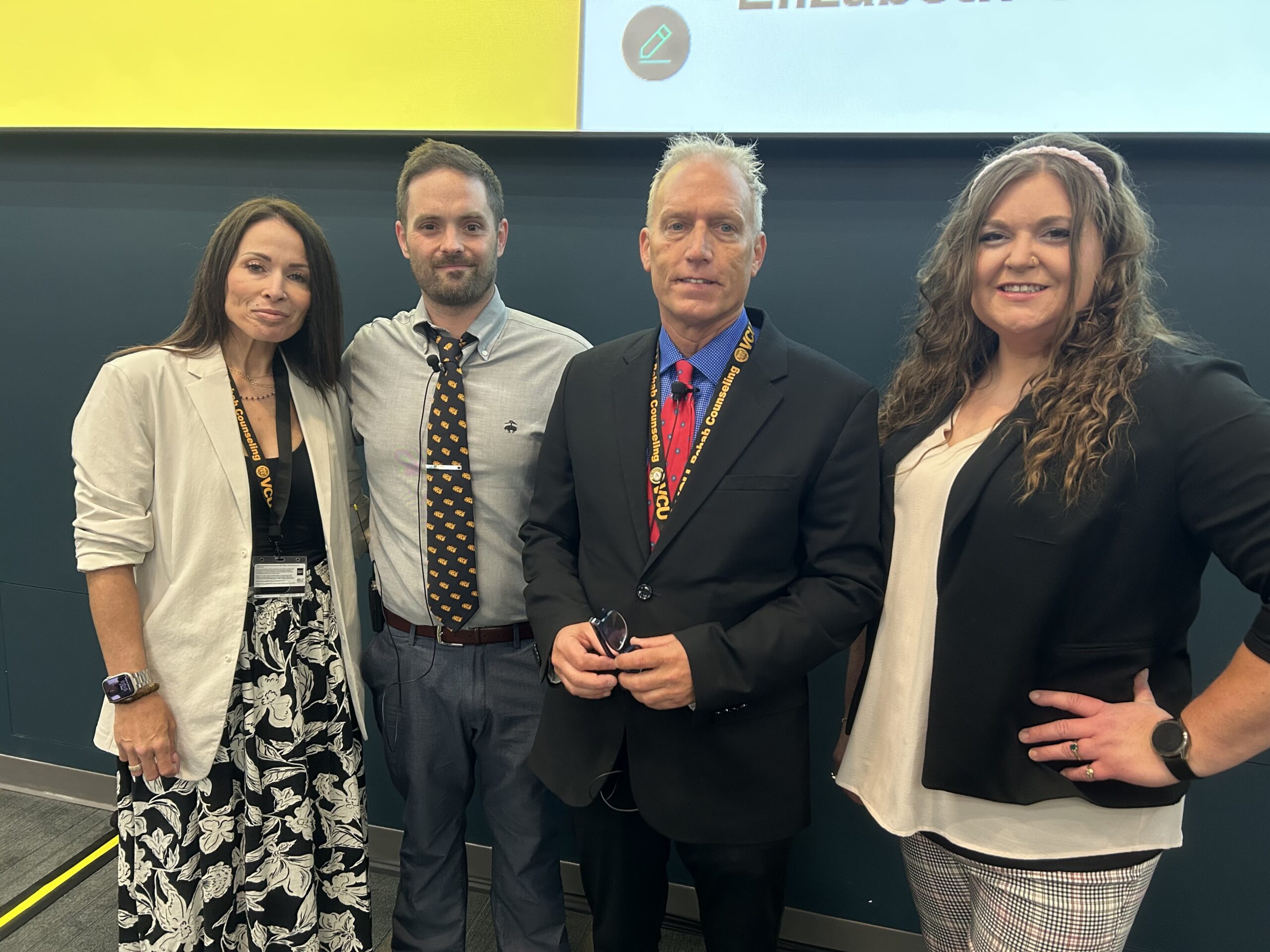 Four people standing in front of a power point presentation