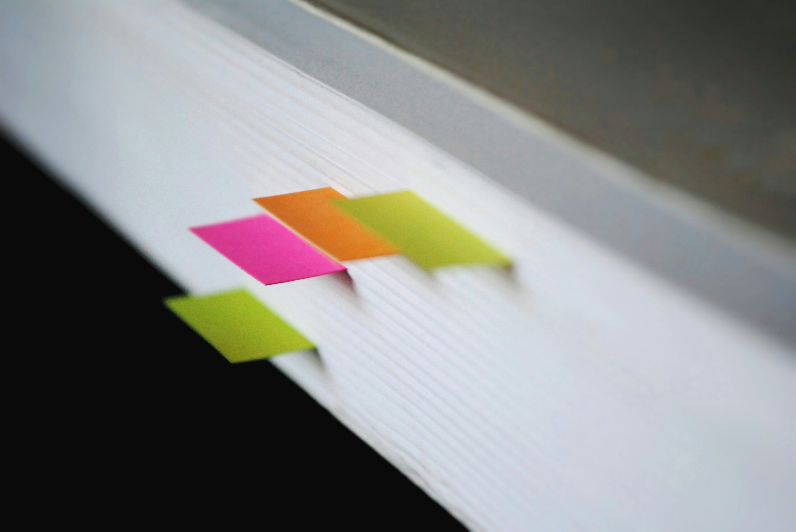 Stack of white paper with yellow, orange, and pink sticky notes sticking out